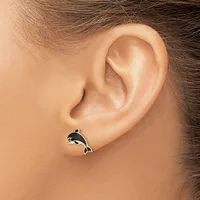 A small silver whale-shaped stud earring with black enamel detail worn in a pierced earlobe.