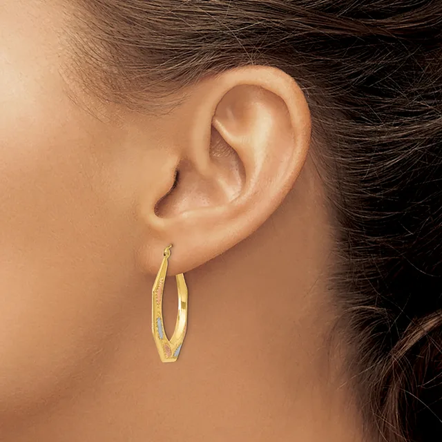 A person wearing gold oval hoop earrings with a textured finish, shown from the side profile displaying the ear and earrings.