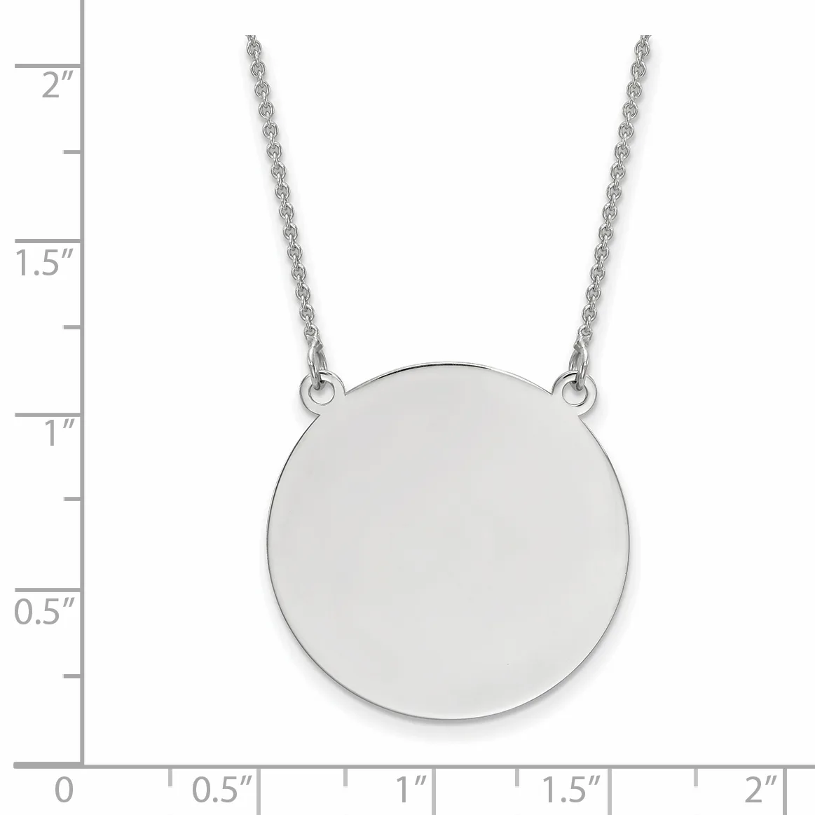 A polished silver circular pendant hangs from a delicate chain, shown against a ruler measuring approximately 2 inches in total length.