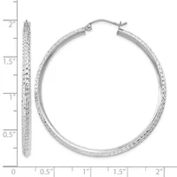 A pair of textured silver hoop earrings with a hammered finish, displayed against a ruler showing they measure approximately two inches in diameter.