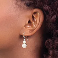 A person wearing silver hook earrings with two stacked white pearl drops on each ear.