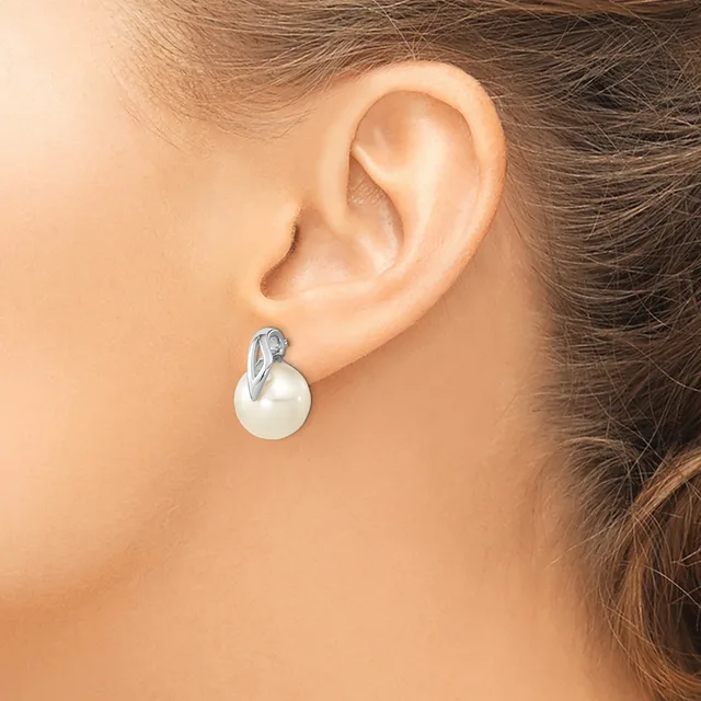 A woman wears a pearl drop earring with a silver bail on her earlobe, shown in profile against her skin.