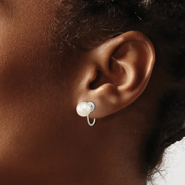 A person wearing a white pearl drop earring with a curved hook fastening, shown from the side profile against their ear.