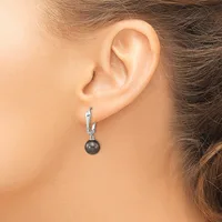 A woman wearing a silver hoop earring with a dark gray pearl pendant hanging from the bottom, shown from the side profile of her ear and neck.