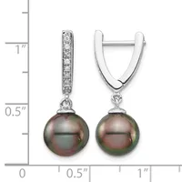 A pair of silver huggie earrings with diamond-set bails and dark tahitian pearl drops, shown next to a measurement scale indicating approximately one inch in length.