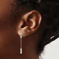A person wearing a long dangling earring with multiple round diamond or crystal stones connected by a delicate chain, shown from the side view of their ear and shoulder.