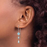 A person wearing a silver threader earring with light blue gemstones in graduated sizes hanging from a delicate chain through the ear.