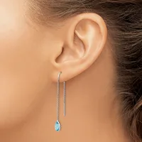 A woman wearing long threader earrings with small blue teardrop gemstones hanging from thin silver chains.