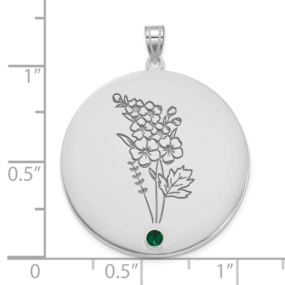 Silver circular pendant with etched floral bouquet design and a small round green gemstone at the bottom, shown next to a ruler for scale.