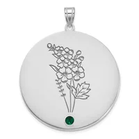 Silver circular pendant with engraved flower bouquet design and a small round emerald-green stone at the bottom, suspended from a silver bail.
