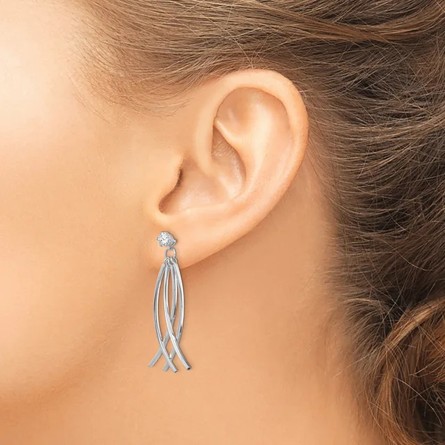 A woman wearing a long tassel earring with a small diamond stud at the top and multiple thin strands hanging down, displayed on her ear.
