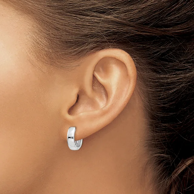 A person wearing a polished silver hoop earring is shown from the side, displaying the earring against their ear and neck.