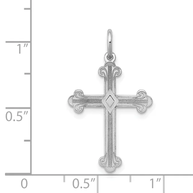 A silver cross pendant with ornate curved ends and a diamond-shaped center detail, shown against a measurement scale indicating approximately one inch in height.