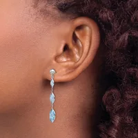 A person wearing a long dangle earring with marquise-shaped stones set in silver metal, shown from the side profile against their neck and shoulder.