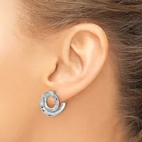 A silver textured chunky hoop earring worn on a person's earlobe, shown from the side view.