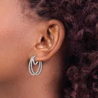 A person wearing textured silver-toned double hoop earrings, shown in profile from the side of their face and ear.