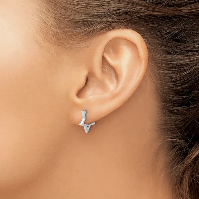 A person wearing a small silver lightning bolt-shaped earring in their earlobe, shown from the side profile.