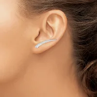 A curved silver ear crawler earring with pavé-set crystals worn on a person's ear, shown from a side profile view.