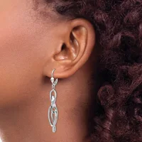 A person wearing a silver chain link drop earring with a lever back closure, shown from the side profile against their ear.