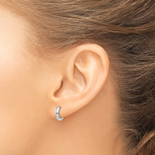 A person wearing a small curved silver hoop earring in their earlobe, shown in profile with brown hair pulled back.