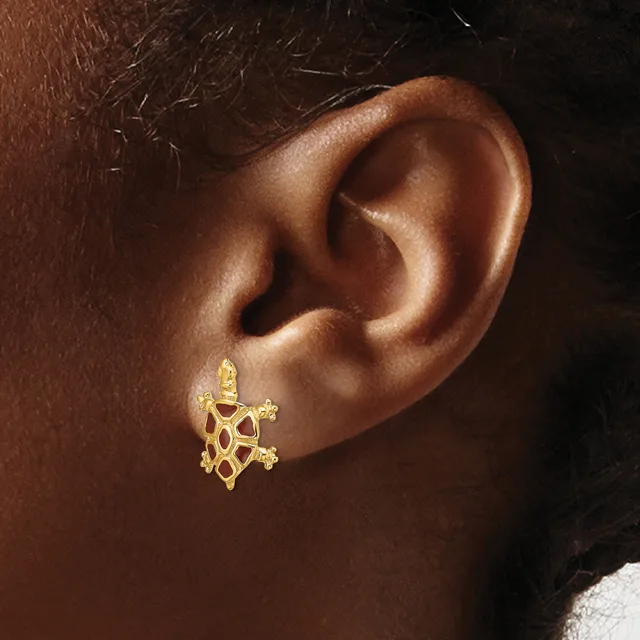 A close-up view of a person's ear wearing a gold turtle-shaped stud earring with cutout details and a post back.