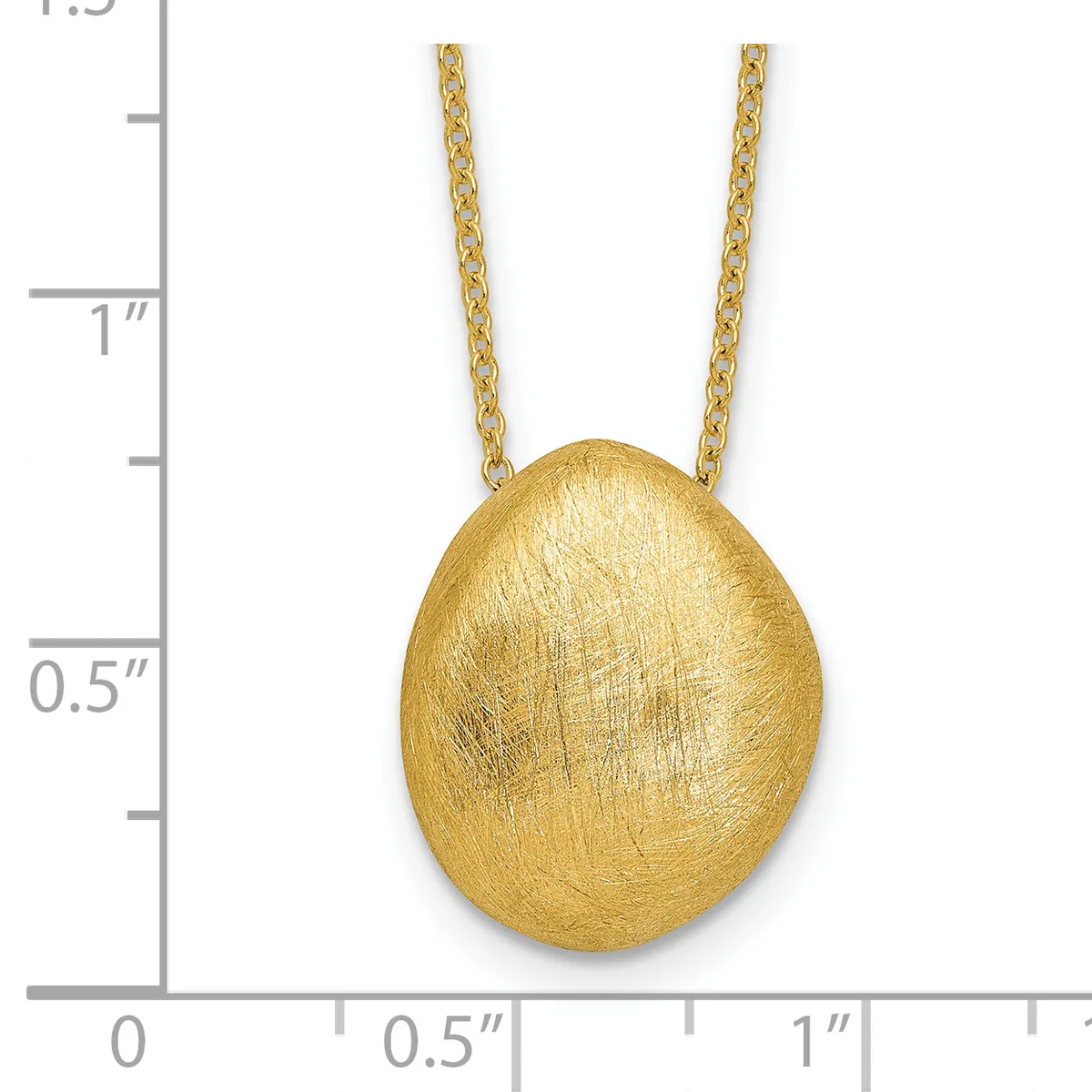 A brushed gold oval pendant hangs from a delicate gold chain against a measurement scale.