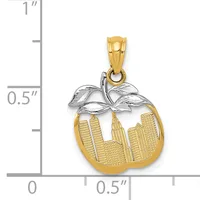 Gold apple-shaped pendant with silver leaf bow at top, featuring cityscape design with buildings, displayed against a ruler showing approximately one inch height.