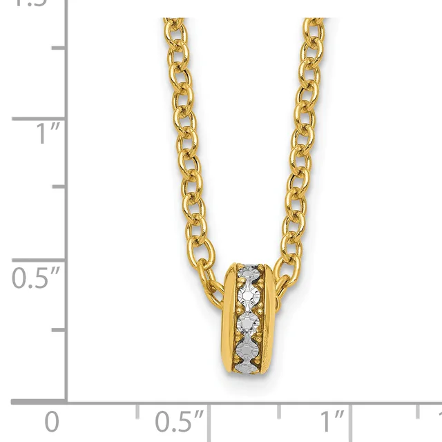 A gold chain necklace with a small cylindrical pendant featuring a band of diamonds set between gold ridges, displayed against a measurement ruler.