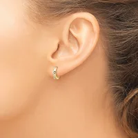 A person wearing a small gold hoop earring with a decorative pattern, shown from the side view of their ear and neck.