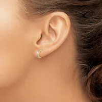 A person wearing a curved crescent-shaped earring with a textured surface in silver and blue-green tones, shown from the side profile of their ear.
