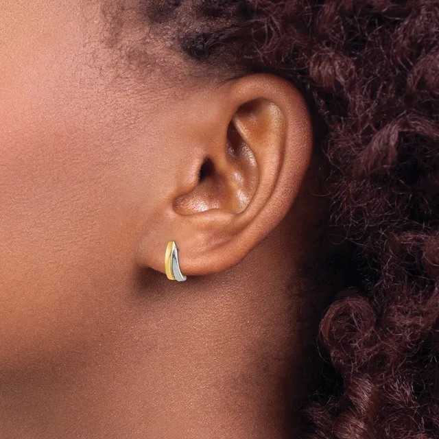 A person wearing a curved silver hoop earring in their earlobe, shown in profile with textured dark hair visible in the background.