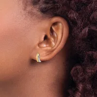 A person wearing a curved silver hoop earring in their earlobe, shown in profile with textured dark hair visible in the background.