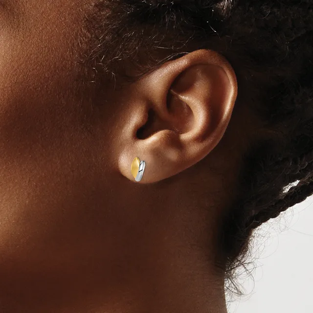 A close-up side view of a person's ear wearing a small polished silver hoop earring.