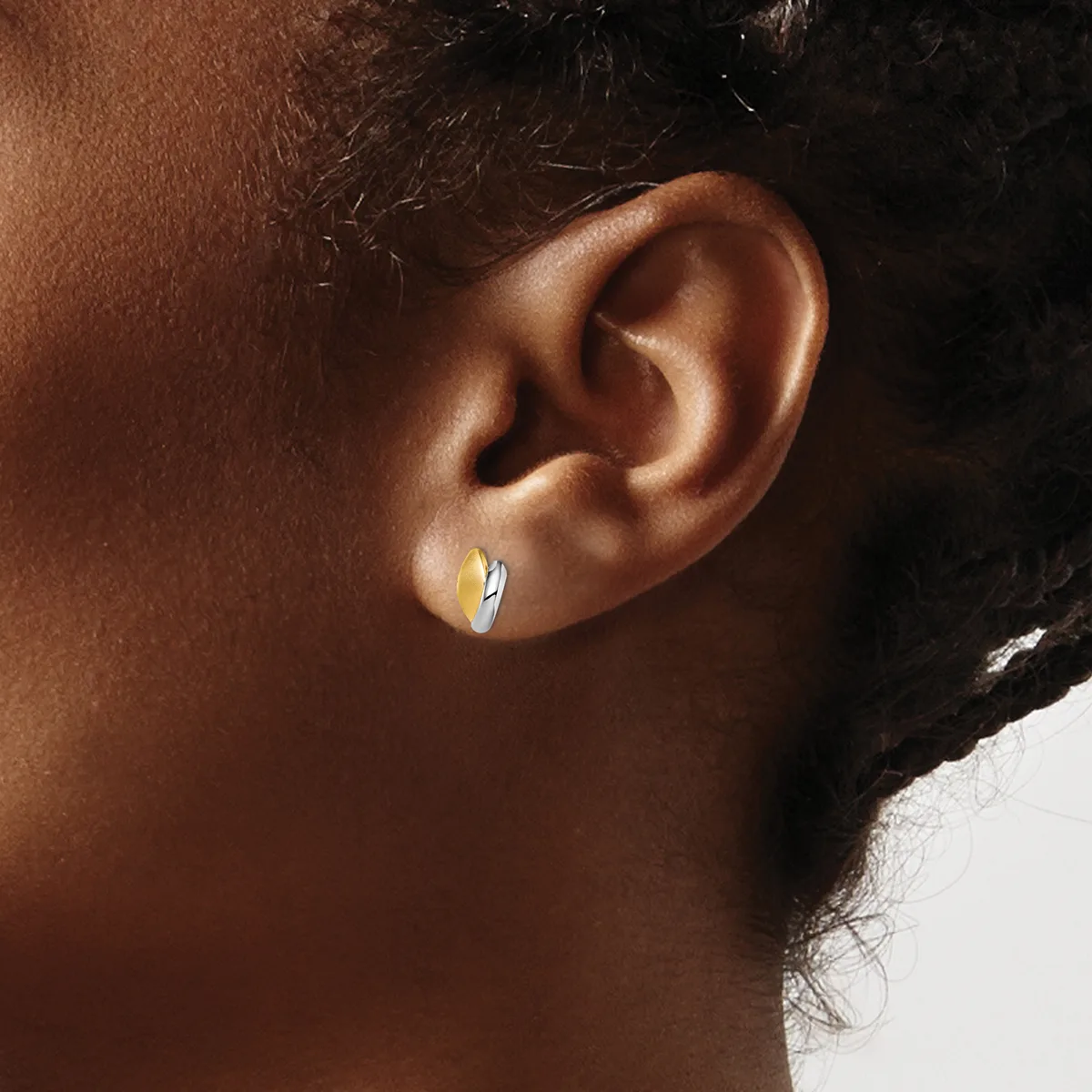 A close-up side view of a person's ear wearing a small polished silver hoop earring.