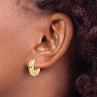 A gold and silver two-tone hoop earring worn on the earlobe of a person with dark skin and textured hair.
