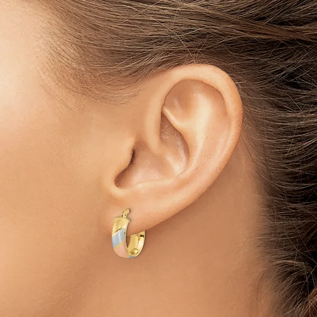 A person wearing small gold and silver two-tone hoop earrings with a polished finish, shown from the side profile.