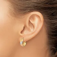 A person wearing small gold and silver two-tone hoop earrings with a polished finish, shown from the side profile.