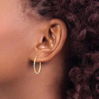 A person wearing small gold hoop earrings is shown in profile from the side of their face and ear against dark curly hair.