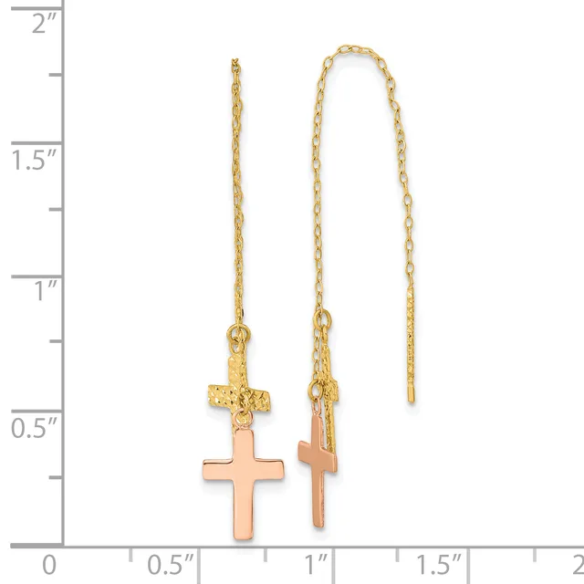 Two gold-toned threader earrings with rose-gold cross pendants suspended from delicate chain links, displayed against a measurement scale.
