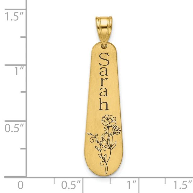 Gold-toned elongated pendant with "Sarah" engraved vertically and a floral design at the bottom, shown against a measurement scale.