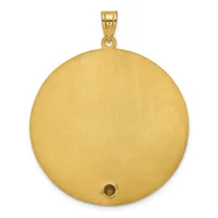 A large circular gold pendant with a brushed finish and a small dark stone or setting near the bottom, suspended from a gold bail.
