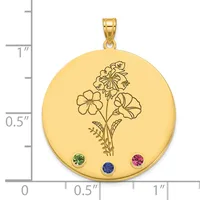 Gold-colored round pendant with engraved flower bouquet design and three small colored gemstones at the bottom, shown next to a ruler for scale.
