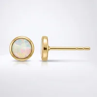 A pair of gold stud earrings with round opal stones set in bezel settings, shown from front and side views against a white background.