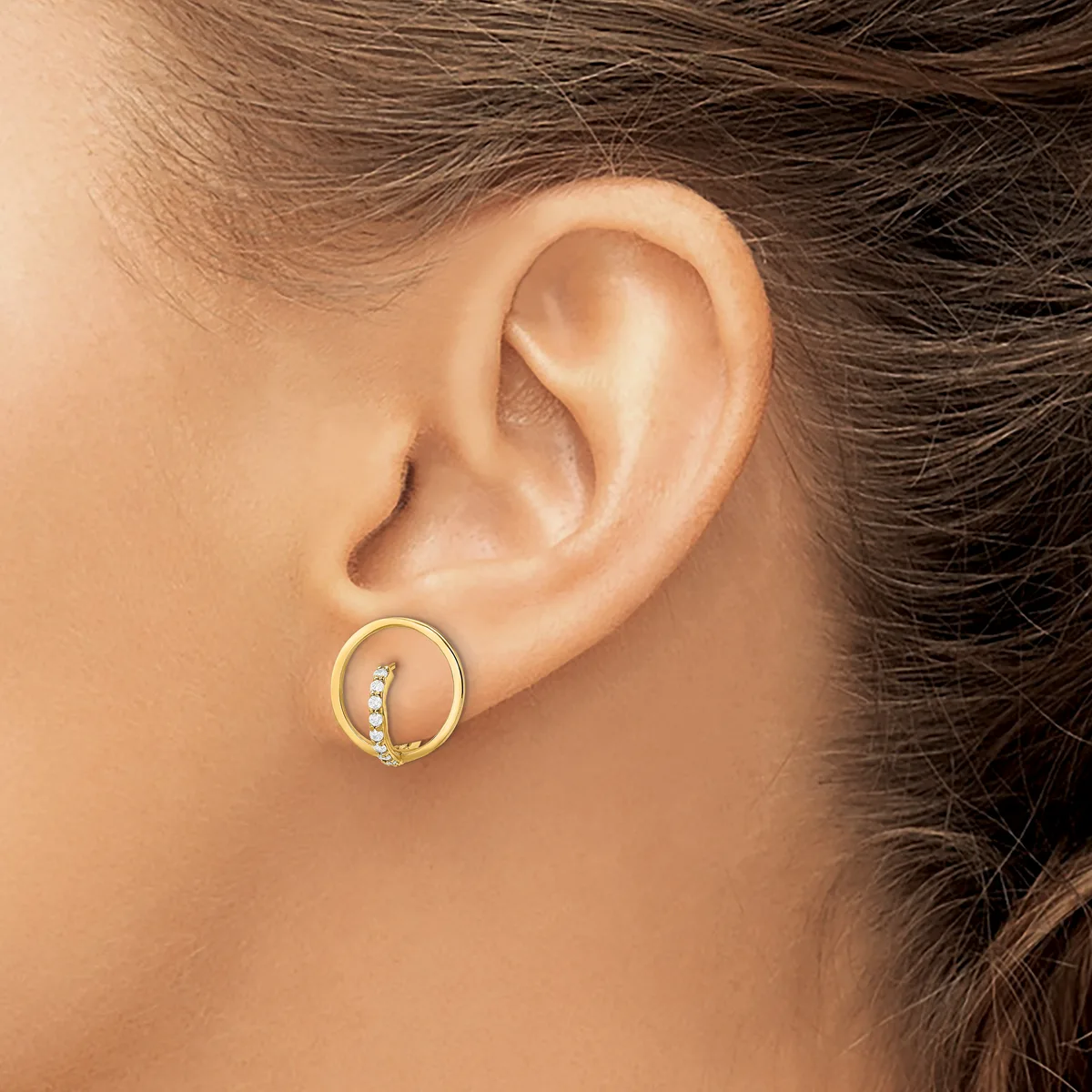 A gold circular earring with small diamonds set along one curved section, worn on a person's earlobe.