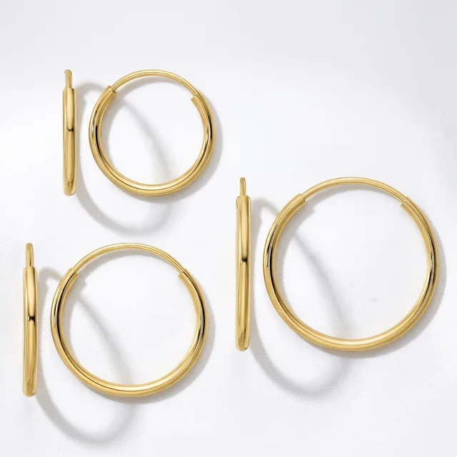 Three pairs of polished gold hoop earrings in varying sizes arranged on a white surface, each pair shown from the front and side view.