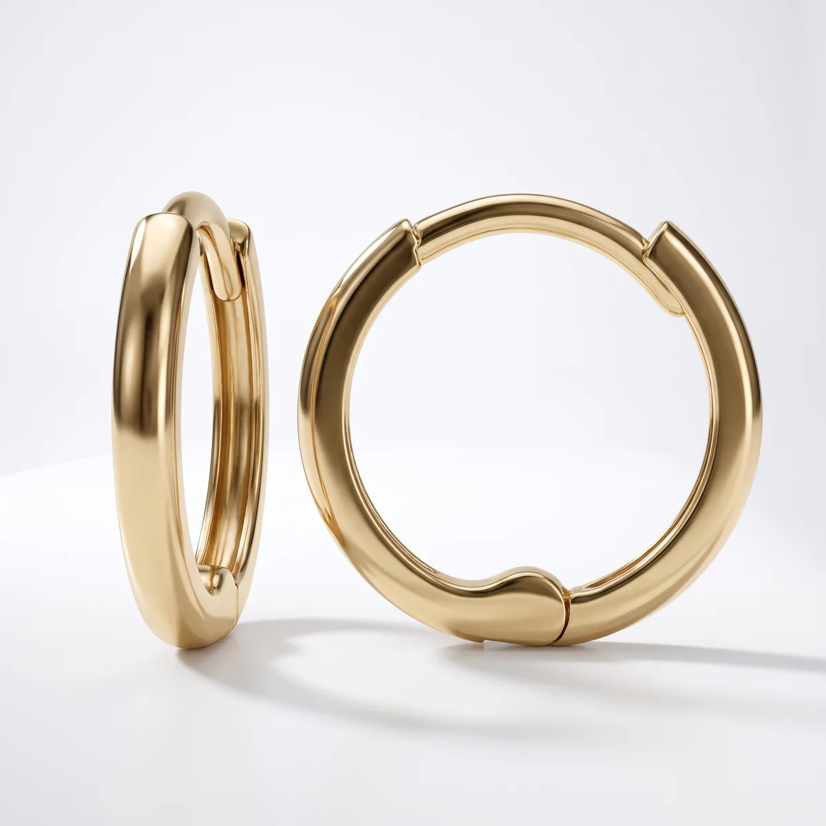 A pair of polished gold hoop earrings with a chunky, rounded profile and hinged closure, displayed against a white background.
