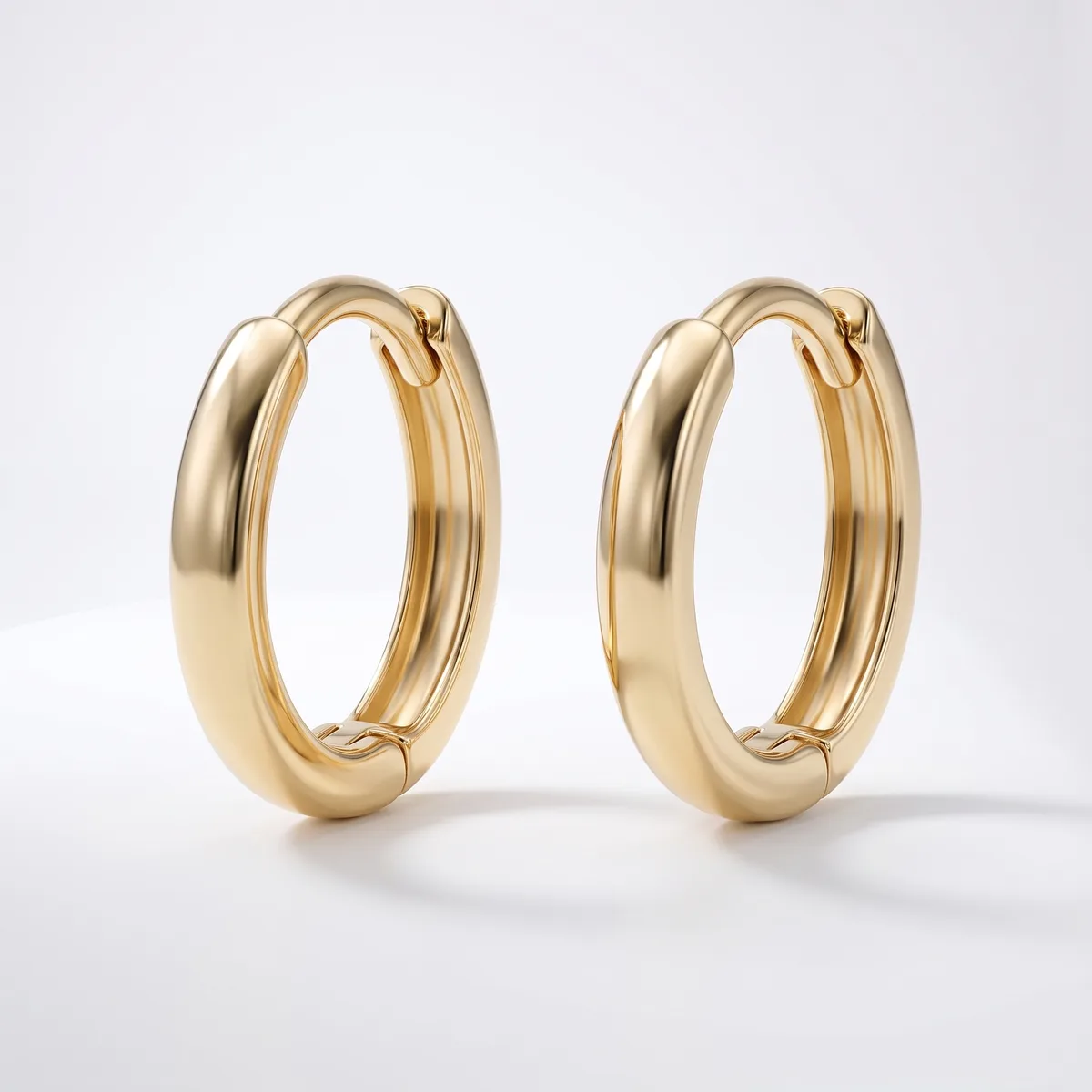 A pair of polished gold hoop earrings with a chunky, rounded profile and hinged closures, displayed against a white background.