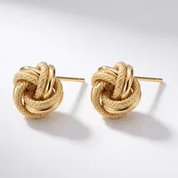 A pair of gold-toned knot stud earrings with a textured finish, displayed against a white background.