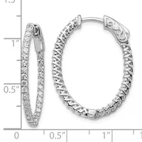Two silver hoop earrings with hinged closures displayed against a measurement scale, one pair diamond-set and one with an ornate textured design.