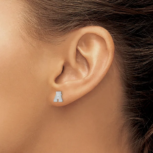 A silver letter A stud earring worn in a pierced earlobe on a person with brown hair.